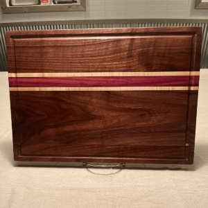 solid dark walnut cutting board with red and white stripes in center